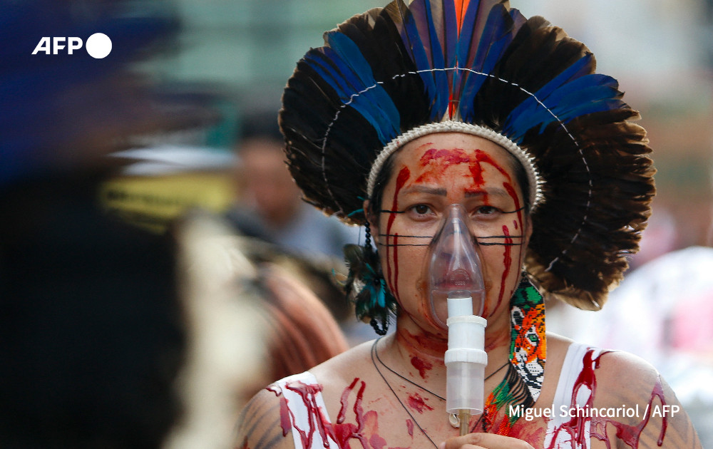 A Brazilian indigenous woman wears a portable oxygen mask during a march for climate justice and against wild fires affecting the entire country in Sao Paulo, Brazil. 
